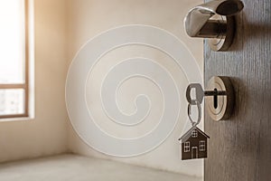 Open door to a new home. Door handle with key and home shaped keychain. Mortgage, investment, real estate, property and new home