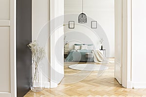 Open door to white bedroom interior with herringbone parquet, ki