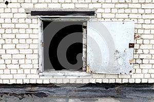 Open door on a white brick wall, darkness