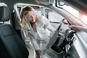 Through open door. Woman in formal clothes is indoors in the autosalon