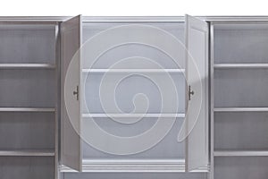 Open doors of a white wooden kitchen cabinet with shelves.