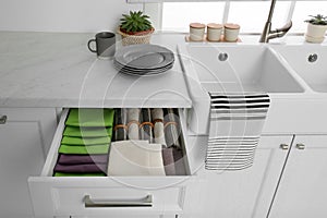 Open drawer with different folded towels and napkins in kitchen