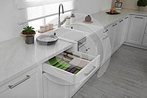 Open drawer with different folded towels and napkins in kitchen