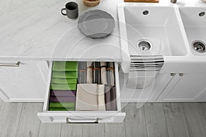 Open drawer with different folded towels and napkins in kitchen, above view