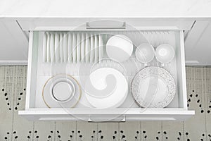 Open drawer with different plates and bowls in kitchen, above view