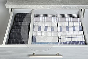 Open drawer with folded towels. Order in kitchen