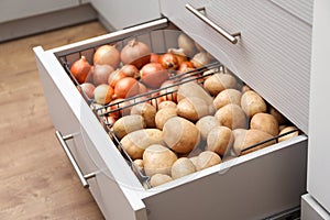 Open drawer with potatoes and onions. Orderly storage