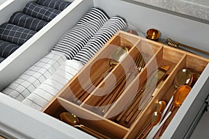 Open drawer with utensils and folded towels. Order in kitchen