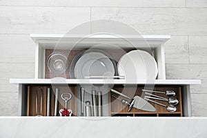 Open drawers with different dishware and utensils in kitchen, top view