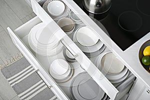 Open drawers with different plates and bowls in kitchen, above view