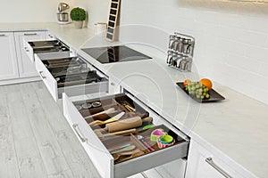 Open drawers with different utensils in kitchen