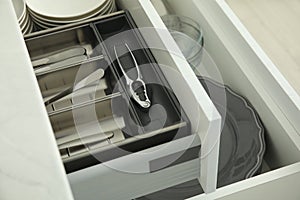 Open drawers of kitchen cabinet with different dishware and utensils, closeup