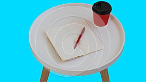 Open empty blank note paper with red pen, red cardboard cup of coffee to go on white round journal wood table isolated