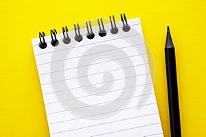 Open, empty blank notebook on a yellow background, spiral notepad on a table. Abstract concept, copy space
