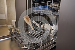 Open empty dishwasher in kitchen. Modern kitchen appliance. Housekeeping equipment, Household chores. Close-up