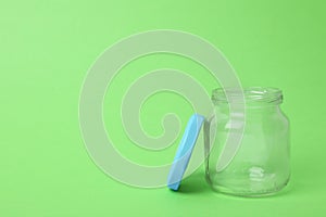 Open empty glass jar on light green background