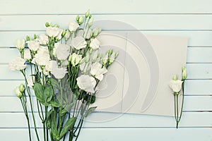 Open empty notebook and bouquet of white flowers eustoma on blue rustic table from above. Woman working desk. Flat lay styling. photo