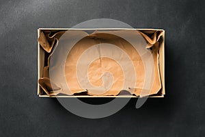 Open empty Shoe box, isolated on a black background. Crumpled brown paper.