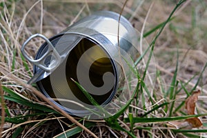 Open and empty tin can in the grass close-up