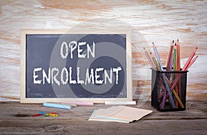 Open Enrollment text on a blackboard. Old wooden table with text