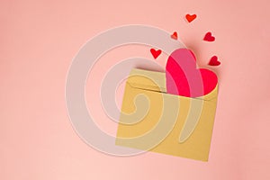 An open envelope made of kraft paper with hearts cut out of felt. Pink background. Mock up. Valentine's Day concept