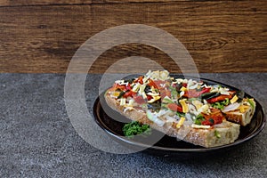 Open-face sandwich on a black plate isolated on a stone pattern.