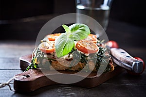 Open-faced toasted cheese sandwich with cherry tomatoes, spinach and fresh basil.