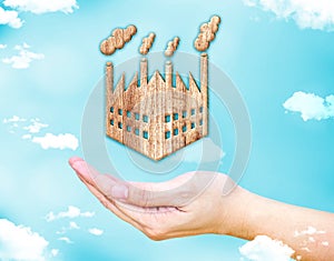 Open female hand with factory wood icon with blue sky and cloud, Ecology concept