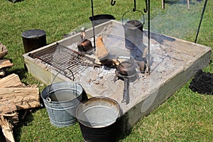 Open fire pit with smoldering fire and variety of pots and pans