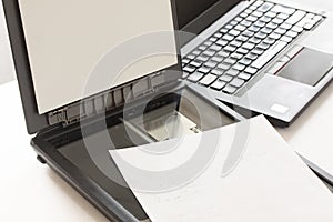 Open flatbed scanner with paper lying on it and a notebook computer in background.Selective focus image