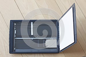 Open flatbed scanner on wooden table. Top view