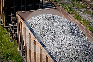 Open freight railway wagon loaded with crushed stone. Freight transportation of bulk building materials by rail. Shot