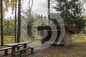 An open gazebo from a tree trunk, benches and a table made of planks, for outdoor recreation. Camping