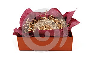 Open gift box with burgundy wrapping paper and shredded paper isolated on white background.