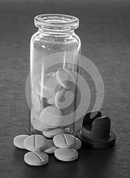 Open glass jar with medications in black and white close-up