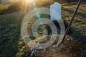 Open grave with shovel at sunset photo