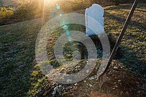 Open grave with shovel at sunset