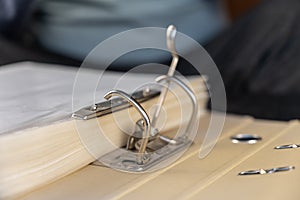 Open gray file folder with metal binder. Papers are on a black desk. Close-up. Selective focus