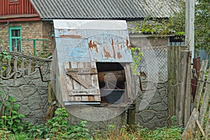 Open gray old well with a bucket near a stone wall