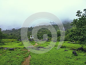 Open Green Grass Land With Mountains in the Background Covered With Clouds