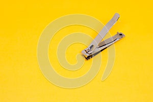 An Open Grey Nail Clipper in The Corner of Yellow Background
