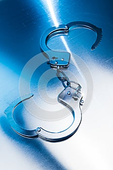 Open Handcuffs on a metallic background with dramatic lighting