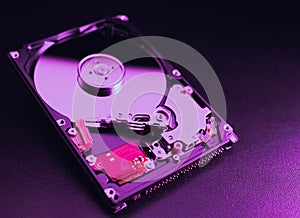 An open hard disk disassembled HDD of a computer or laptop lies on a purple surface. Computer hardware and accessories. Hard disk