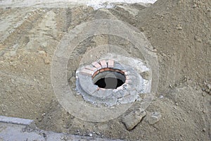 open hatch, destroyed asphalt, sand and rubble left after road repair