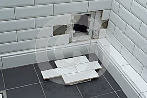 Open hidden revision sanitary hatch on the wall of tile under the bathroom.