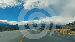 Open Highway in Desert Landscape, A quiet highway stretches into the distance, flanked by desert mountains and a cloudy