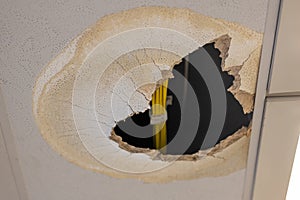 An open hole in the ceiling caused by a water damage.