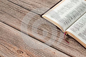 Open Holy Bible Book with golden pages on a rustic wooden table with copy space