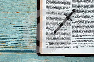 Open Holy Bible Book with a sword on blue wooden background with copy space