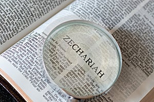 Open Holy Bible Book Zechariah prophet Old Testament Scriptures with a magnifying glass